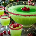 Festive Grinch Punch in a punch bowl with Christmas decorations around it.