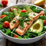 Delicious and healthy salmon salad recipe with fresh greens, cherry tomatoes, avocado, and grilled salmon.